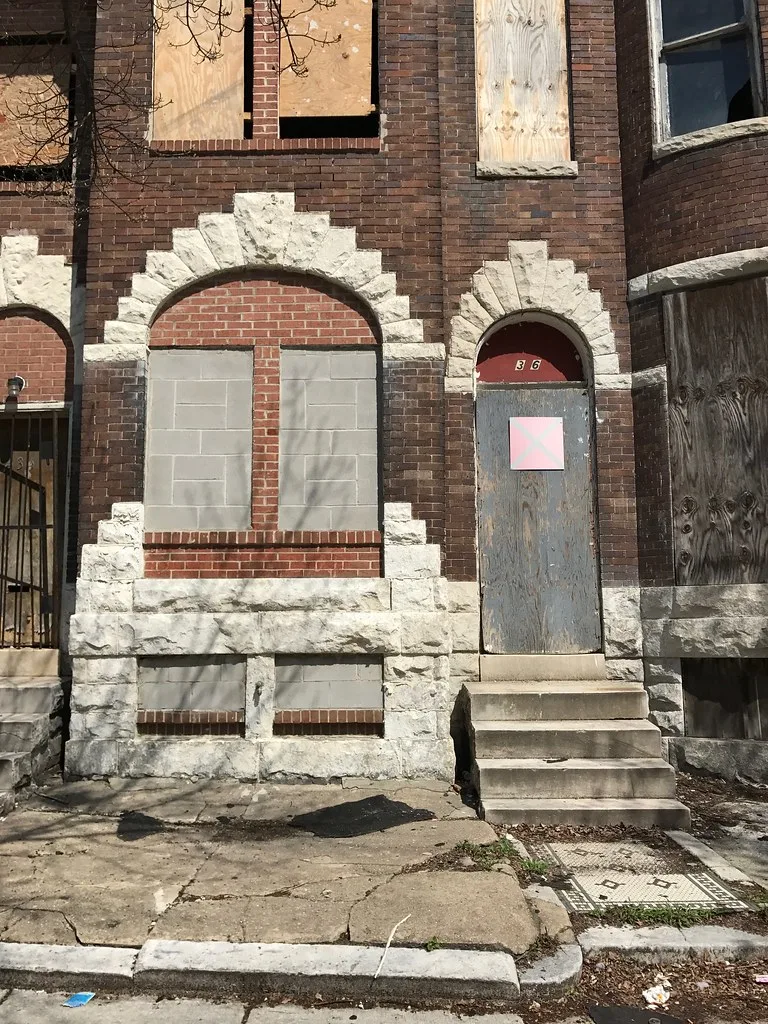 Old brick facade with bricked-up or boarded openings.