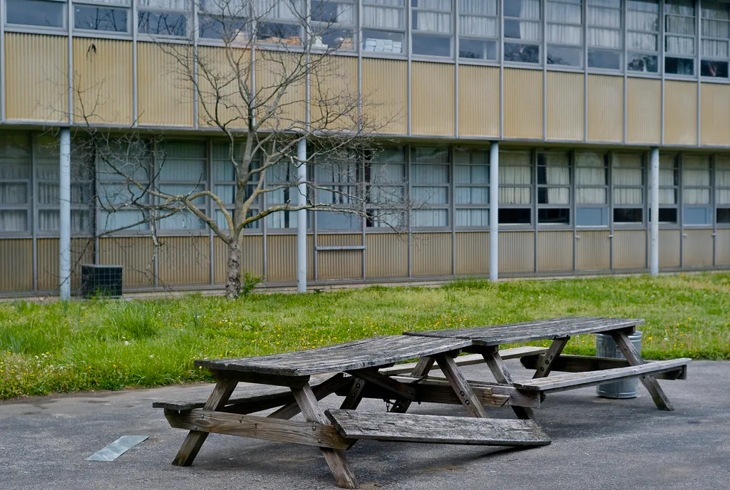 Weathered picnic table in front of a building with broken windows.