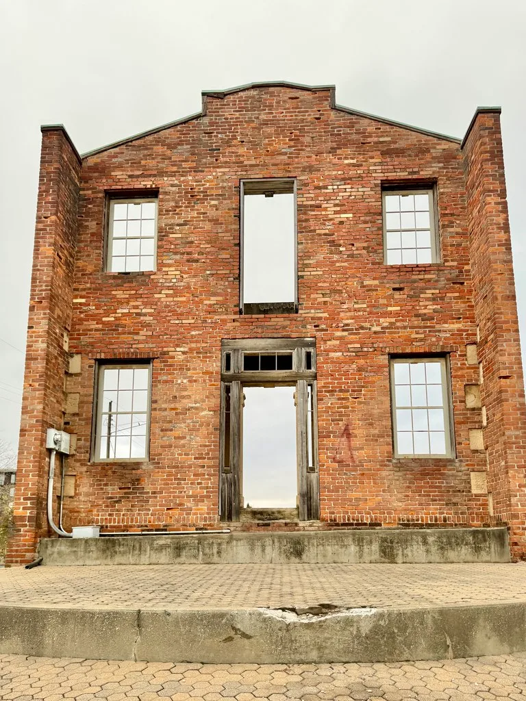 Isolated brick facade with openings looking onto the sky.