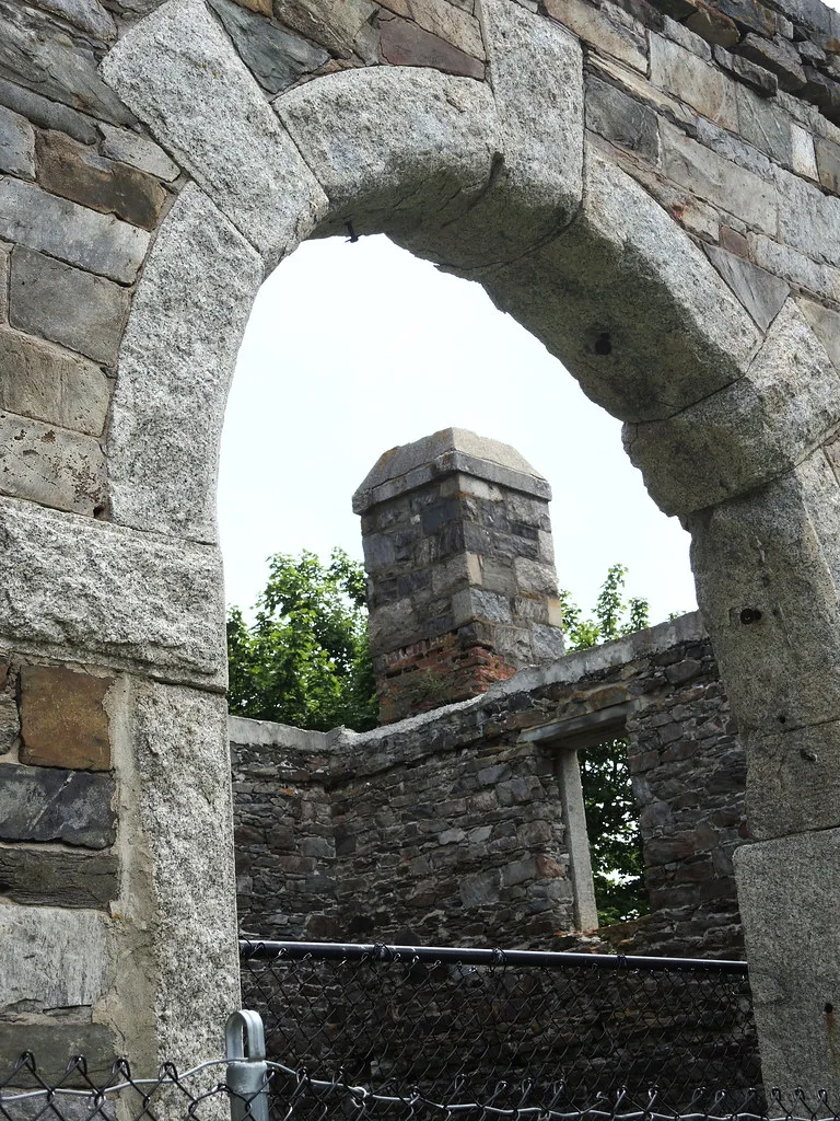 Stone arch in front of roofless walls and an old chimney.