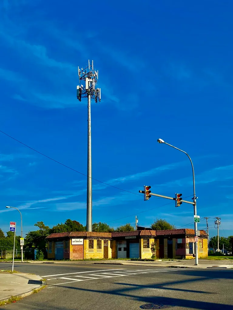 Closed old yellow and red garage at an intersection beneath a tall antenna.