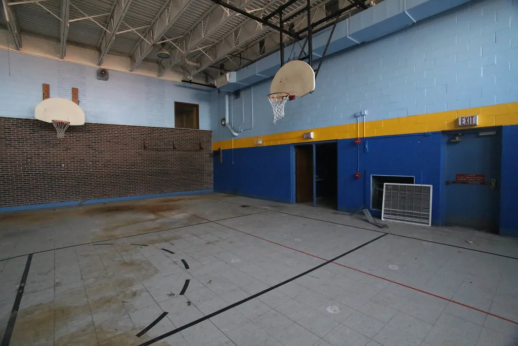Empty old gym with blue walls and a deteriorated floor.