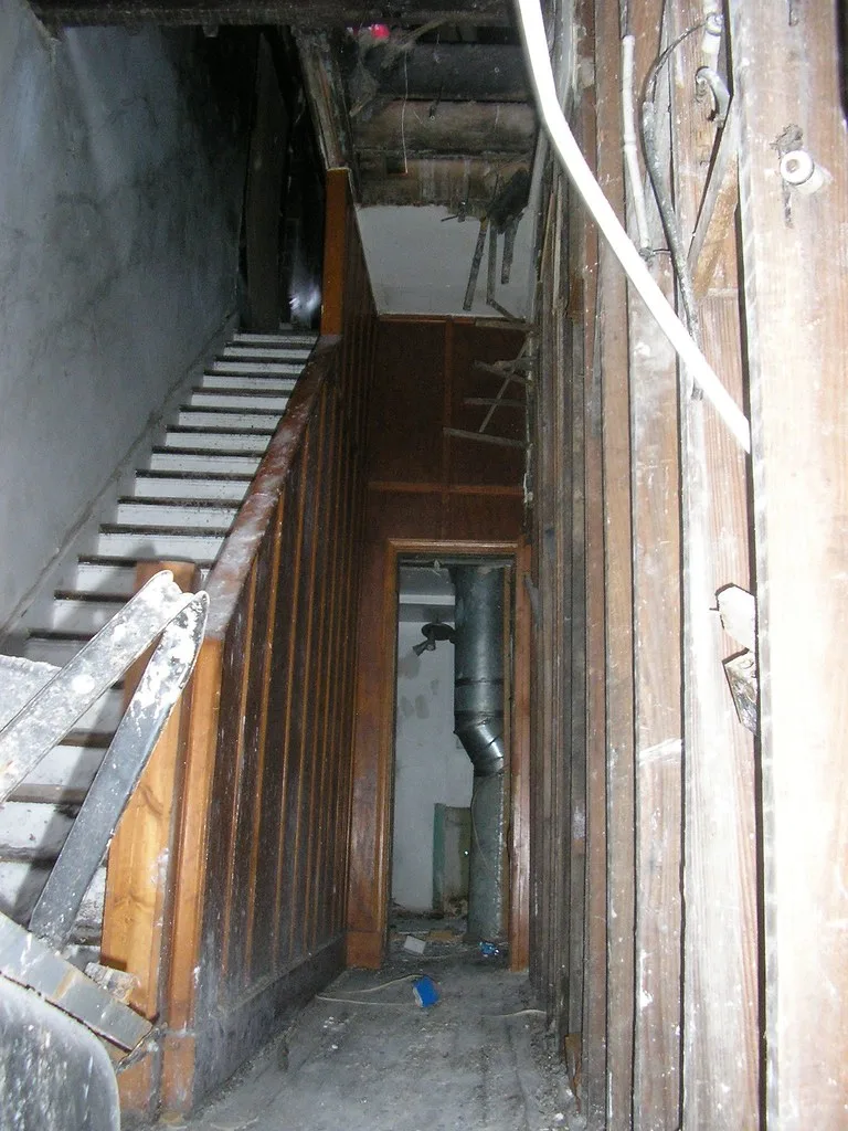 Wooden staircase in an interior with damaged walls and ceiling.
