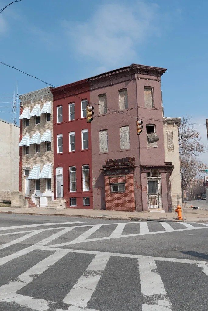 Three-storey pink building with boarded windows at a street junction.