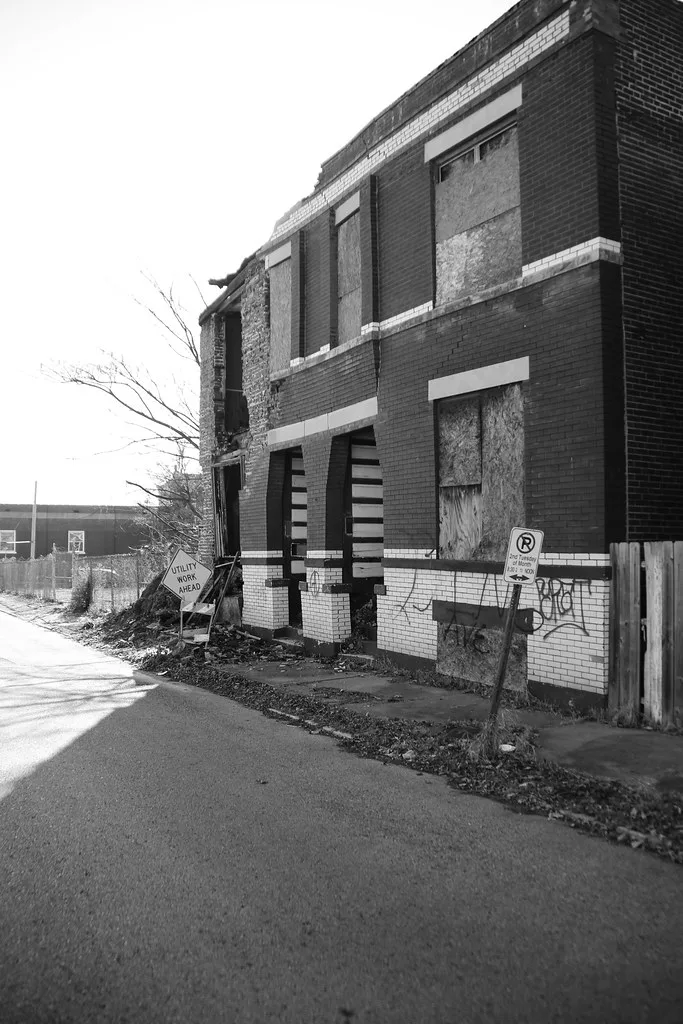 Boarded and partly collapsed brick building in black and white.