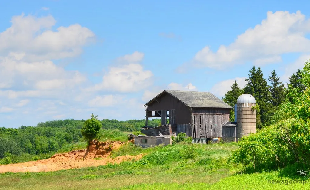 Ancienne grange de bois partiellement effondrée près d’un silo.