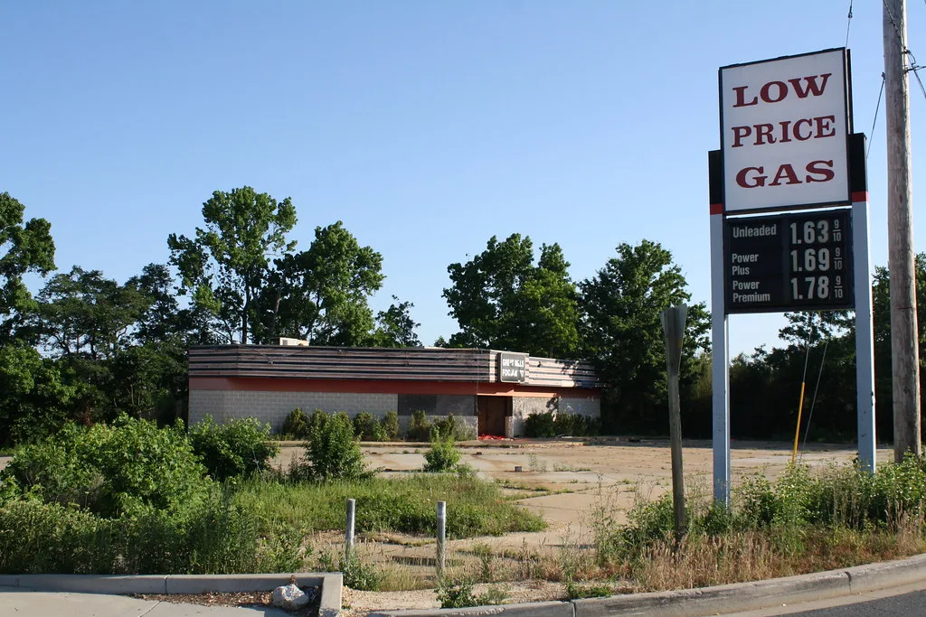 Old filling station with missing pumps and an overgrown forecourt.