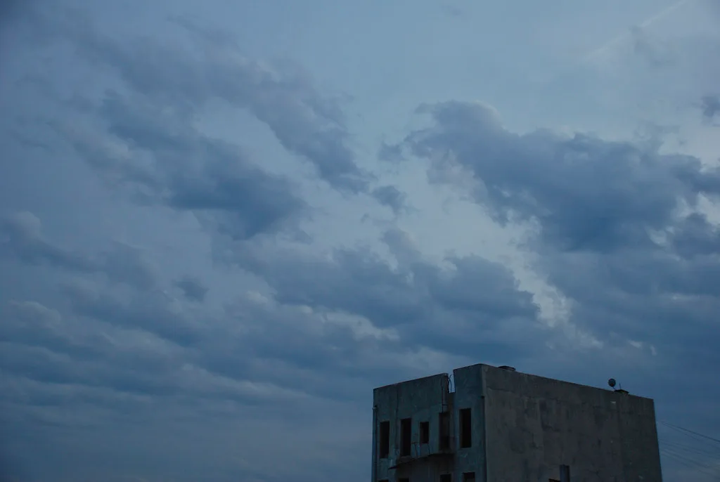 Upper part of a deteriorated building beneath a dark cloudy sky.