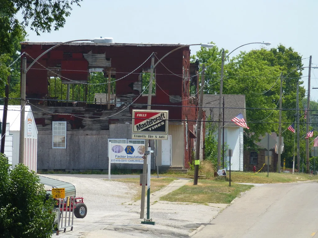 Ruined red and white building with exposed upper-floor framing beside a street.
