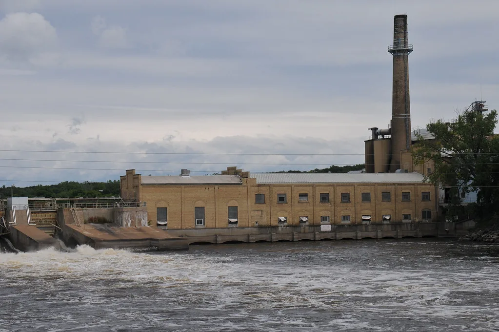 Former Sartell Paper Mill beside the water with its tall chimney.