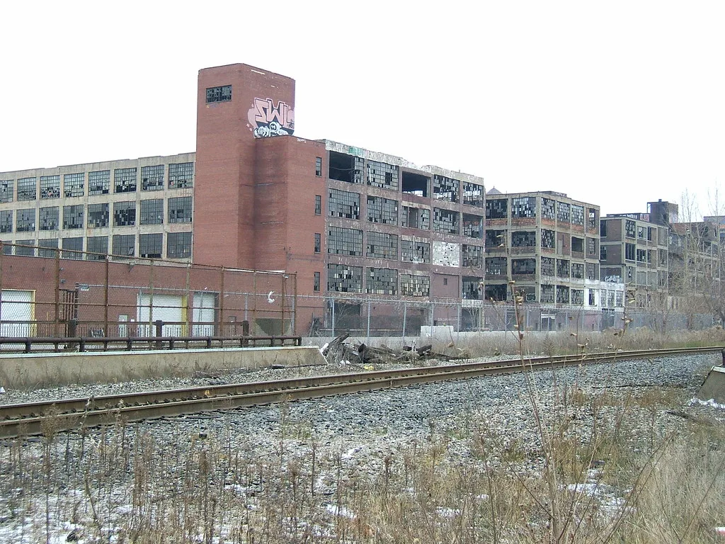 Old factory with broken windows behind a railway track.