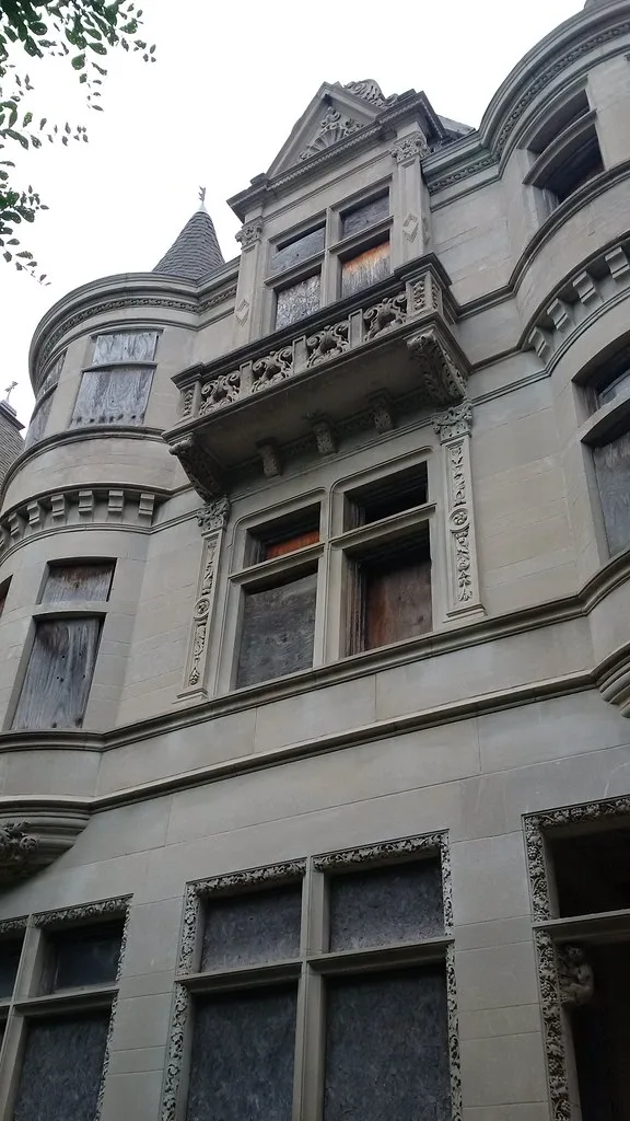 Ornate facade with turrets and a balcony, its windows sealed with boards.