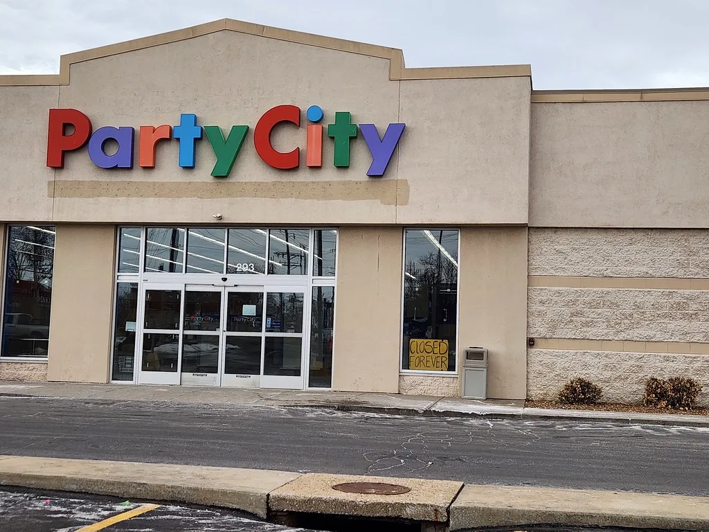 Glazed entrance of a former Party City store with a closure notice.
