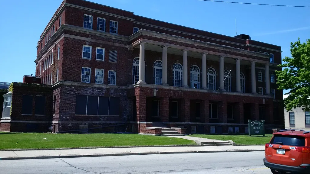 Large brick building with a colonnade and boarded windows.