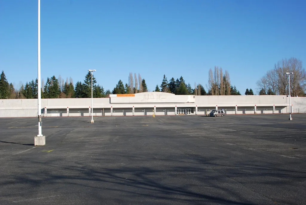 Ancien magasin vide donnant sur un vaste parking.