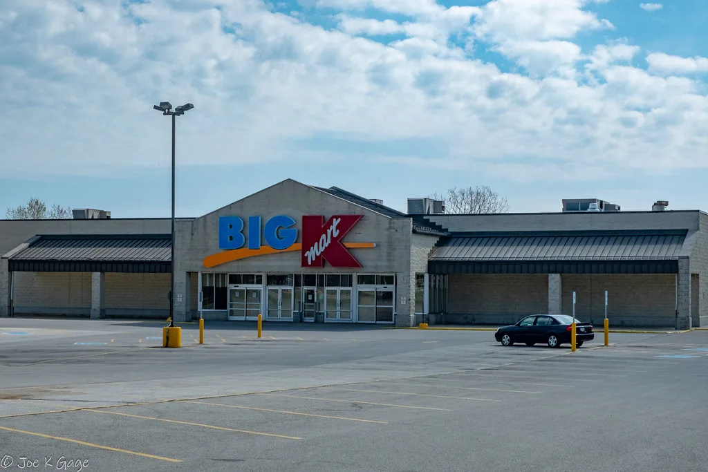 Façade d’un ancien magasin Kmart fermé devant un parking presque vide.