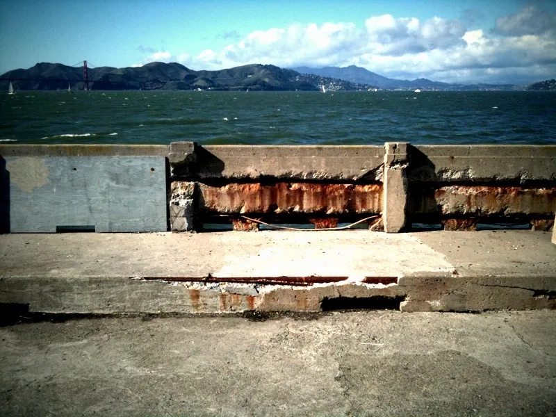 Parapet et sol d’une jetée dégradée au bord d’une baie.