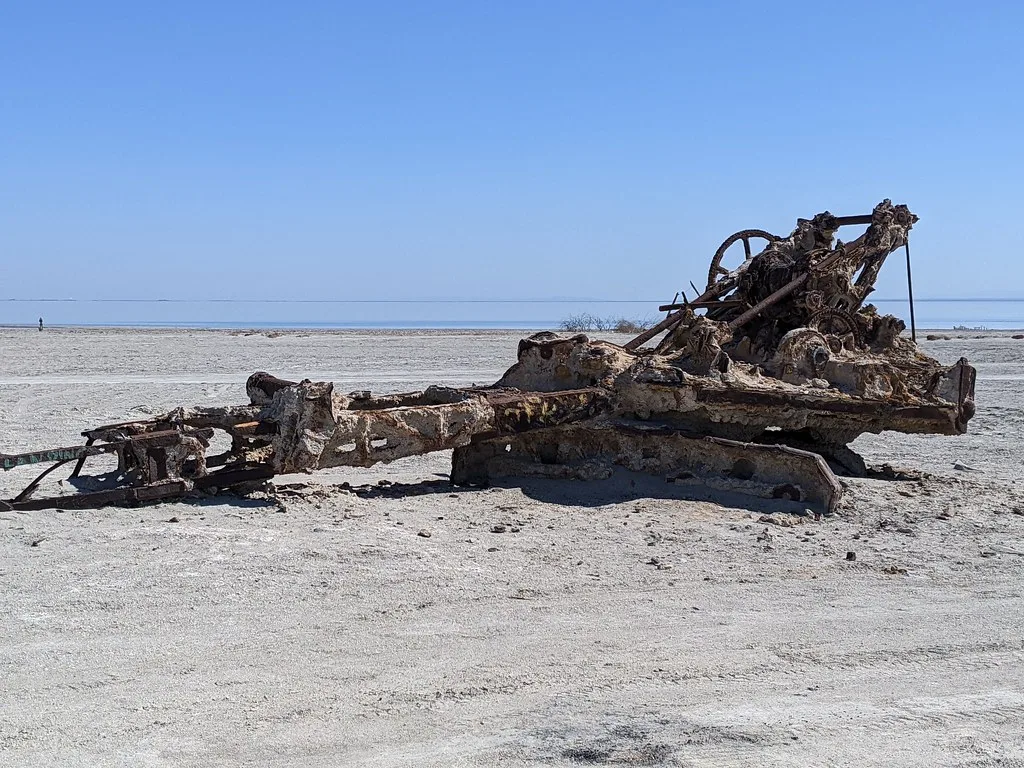 Vestiges de machine industrielle rouillée sur un rivage désertique.