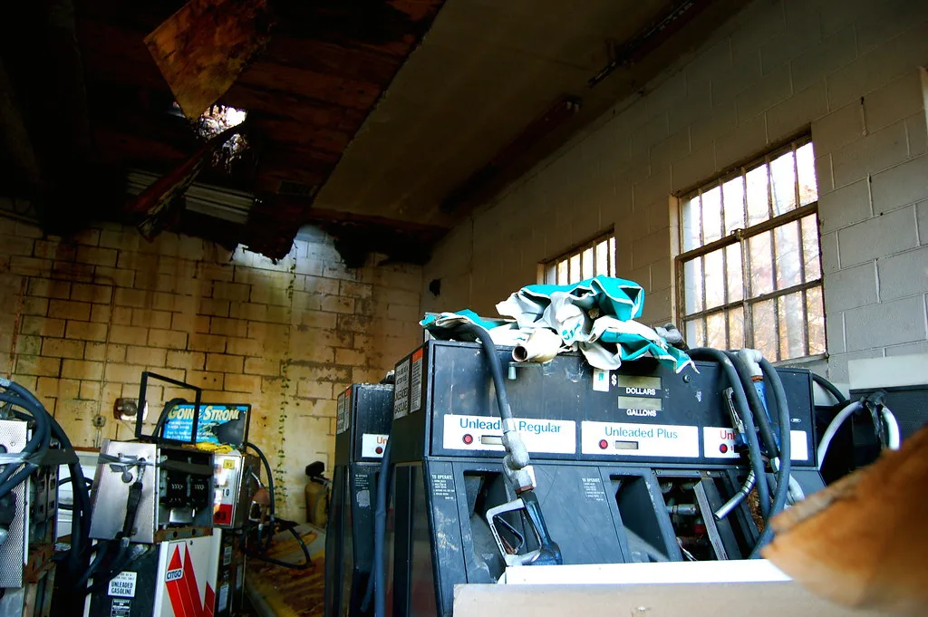 Old fuel pumps stored in a workshop with holes in its roof.