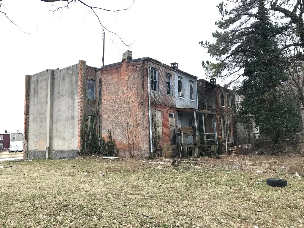 Rear of derelict brick houses with collapsed porches and empty openings.